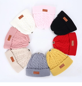 Détail de bonnets en maille tressée en huit couleurs avec étiquette en cuir