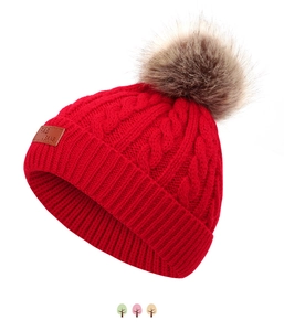 Détail du bonnet d'hiver rouge en tricot torsadé avec pompon en fausse fourrure et étiquette