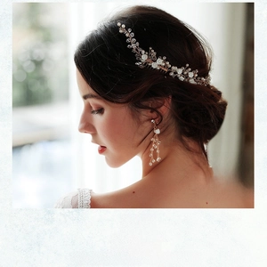 Detail of bridal hair comb and pearl earrings set with white flowers and crystals