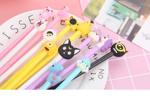 Flat lay of colorful cartoon gel pens with various cute animal silicone toppers on a plate