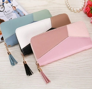 Detailed view of color-block long wallets with tassel zippers on a wooden table