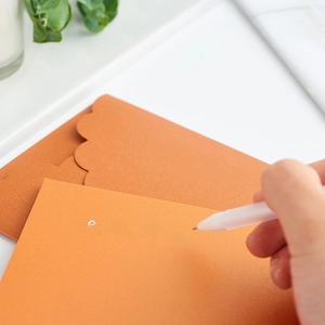 Orange pearlescent paper envelope set with wavy edges and handwritten heart card