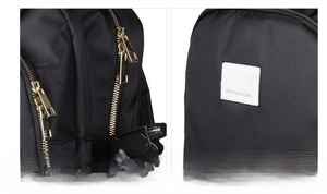 Detail of barber backpack showing gold two-way zippers and professional logo patch