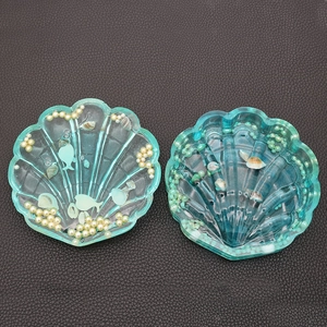 Detail of shell-shaped resin trays in mint and blue with embedded pearls and seashells