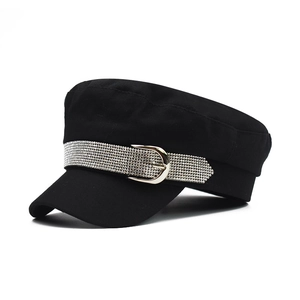 Detail of black military cap featuring a silver rhinestone band and metallic buckle