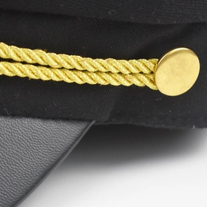 Détail d'une casquette de marin noire avec cordon doré tressé et bouton en métal doré