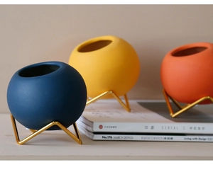 Detail of colorful ceramic sphere vases on golden geometric metal stands for home decor