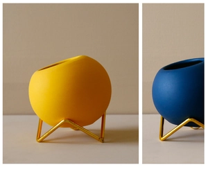Close-up of modern ceramic vases in blue and yellow with golden metal geometric wire stands