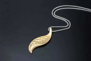 Close-up of golden leaf pendant with fine vein texture and silver box chain
