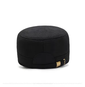 Detail of the golden metal buckle on the back of a black wool flat top military cap