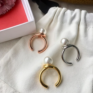 Detailed view of pearl knot rings in rose gold, gold, and silver finishes on white pouch