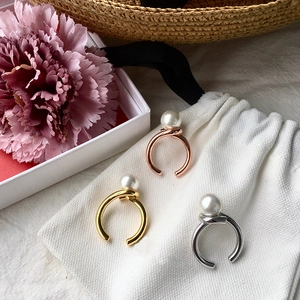 Close-up of gold, silver, and rose gold pearl knot rings on a white pouch