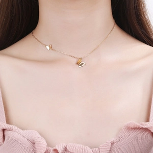 Detail shot of a layered gold butterfly pendant necklace worn on a model neckline
