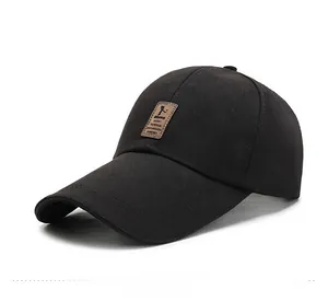Dettaglio di un berretto da baseball nero con patch in pelle marrone e logo sportivo