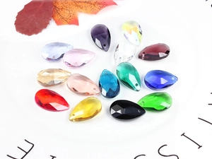 Macro shot of 14 multi-colored teardrop crystal beads for jewelry making on white tray