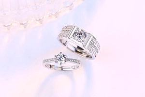 Detailed view of silver couple rings featuring Greek fret patterns and six-prong diamond setting