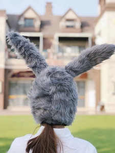 Rear view of long grey faux fur bunny ear hat with plush texture against a park background