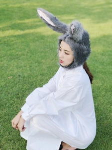 Detailed view of gray plush rabbit ear headwear on a model in an outdoor setting