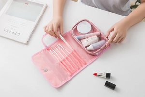Pink waterproof travel organizer showing brush slots and transparent inner zipper pouch