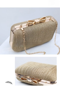 Detail of champagne gold evening clutch with shiny sequins and a bow-knot metal clasp