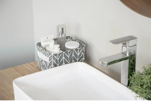 Detail of grey canvas storage basket with white chevron pattern and side handle on a counter