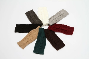 Top view of eight colorful knit fingerless gloves with cable patterns on white background