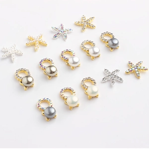 Macro shot of starfish and pearl nail art charms with gold and silver metal accents