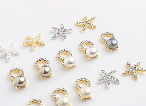 Detailed view of starfish and pearl nail charms with rhinestones in gold and silver