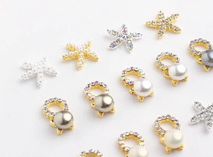 Detailed view of metal starfish and pearl nail charms with rhinestones for DIY art