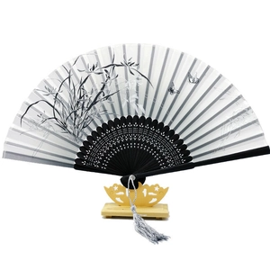 Chinese folding fan with orchid pattern, black carved ribs and grey tassel on wood stand