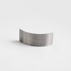 Macro detail of curved minimalist metal hair clip with brushed stainless steel finish