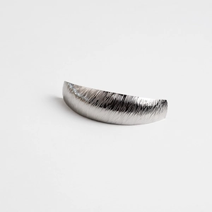 Detail of arched metal hair clip with brushed silver texture and elegant matte finish
