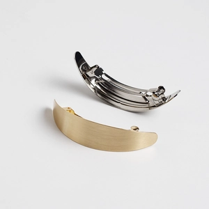 Detailed view of curved gold matte brushed and silver polished metal spring hair clips