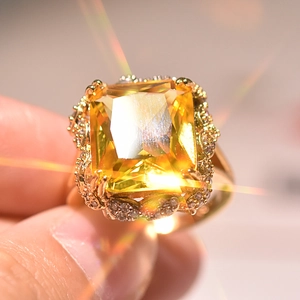 Detailed macro shot of a gold-plated ring featuring a large square yellow gemstone center
