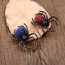Macro shot of spider-shaped brooches with colorful rhinestones on a dry leaf