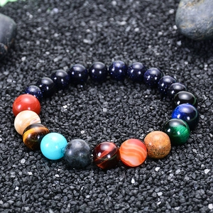 Macro detail of Solar System planet bracelet with natural stones on dark mineral background