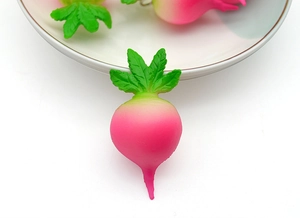 Macro detail of a realistic pink radish keychain charm with vivid green leaves on white ceramic