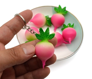 Close-up of a pink radish keychain pendant with green leaves and a metal ring