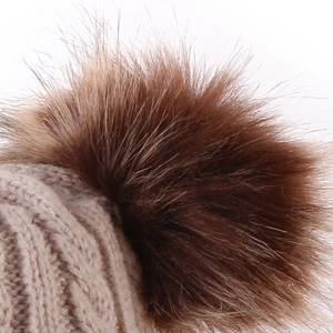 Detailed macro view of beige cable knit baby hat with soft brown faux fur pom poms