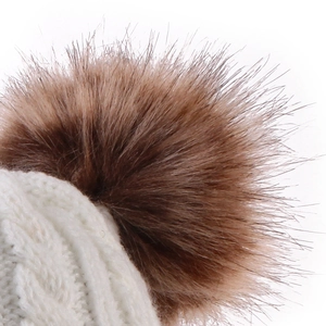 Macro detail of soft cable knit texture and fluffy brown faux fur pompom on baby winter hat