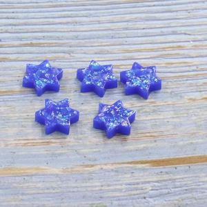 Five blue synthetic opal Star of David charms with shimmering fire on wood surface