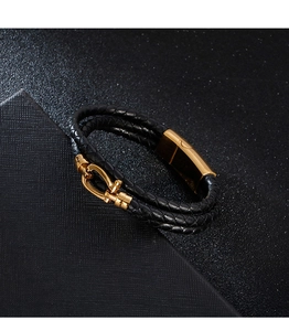 Close-up of black braided leather bracelet featuring a polished gold horseshoe buckle clasp