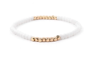 Detail of white matte round beads and gold cube spacers on a stretch beaded bracelet