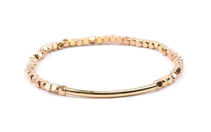 Detailed shot of gold-plated curved tube and metallic cube beads on an elastic bracelet