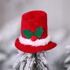 Mini Christmas top hat decoration with holly leaf detail on a snowy pine tree branch