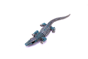 Macro detail showing gradient blue rhinestones and silver metal on crocodile brooch