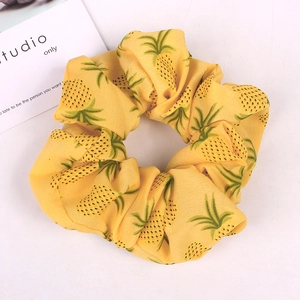 Detail shot of yellow fabric scrunchie featuring a vibrant pineapple pattern with soft texture