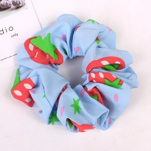 Detail of blue strawberry pattern fabric scrunchie showing texture and elastic design