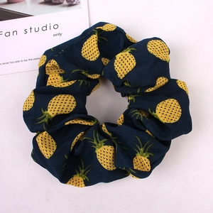 Detailed flat lay of soft navy blue scrunchie with yellow pineapple patterns and elastic band