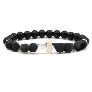 Detail of elastic beaded bracelet with matte black stones and a white cross charm